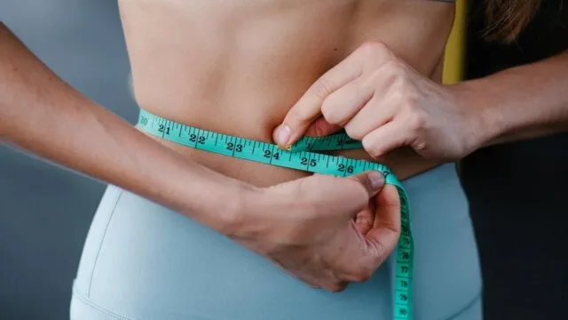 Woman measuring waist for lasting weight loss results