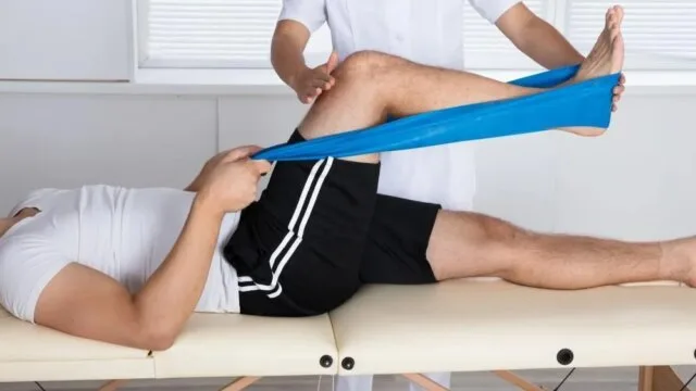 Physical therapist performing knee rehabilitation with resistance band for ACL injury recovery