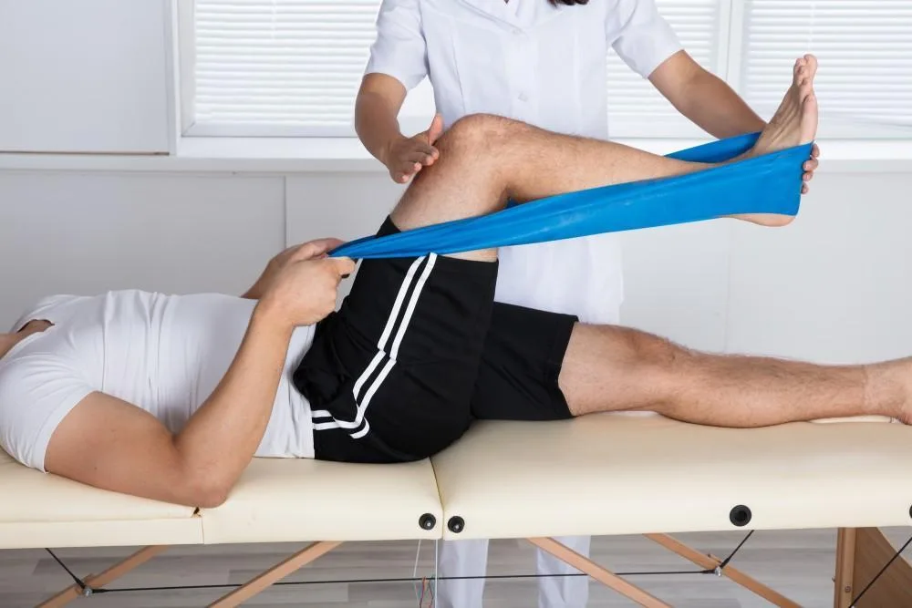 Physical therapist performing knee rehabilitation with resistance band for ACL injury recovery