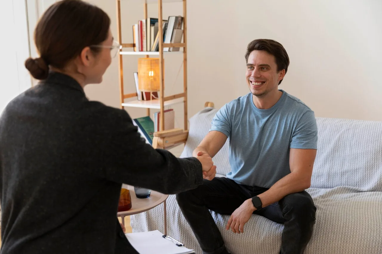 A therapist and patient shaking hands during a mental health therapy session