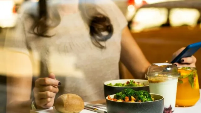 Woman using phone app to track healthy eating for Noom weight loss program