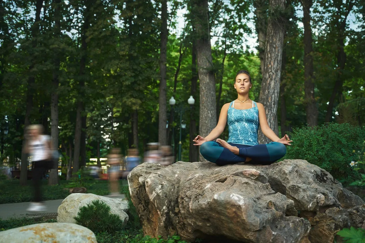 Woman meditating outdoors on rock representing present-moment awareness and mindfulness practice