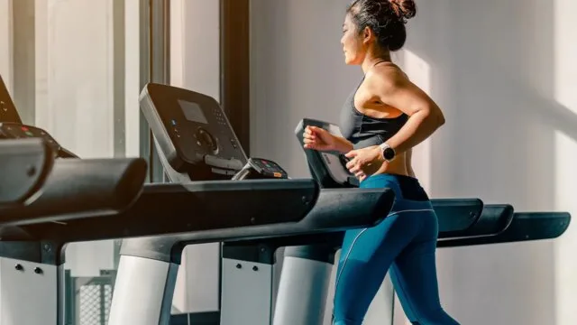 Woman running on a treadmill in a bright gym during a cardio workout