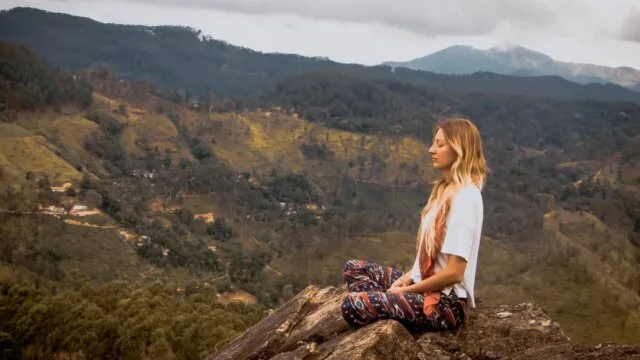 Woman practicing mindful self-care in nature, supporting holistic wellness, stress relief, better sleep, and body awareness.