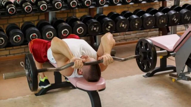 Man performing barbell triceps press on bench representing JM press technique for bigger stronger triceps