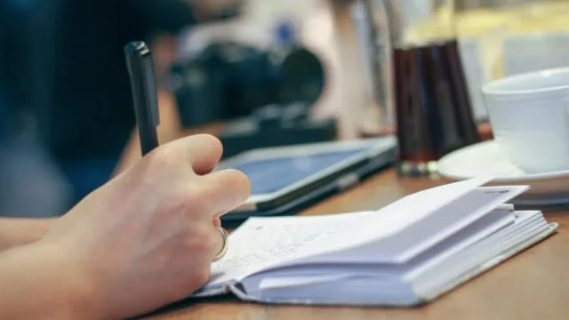 A close-up of a hand writing in a notebook with a pen, representing journaling as a mindfulness and self-reflection practice for deeper subconscious exploration and lasting personal change.