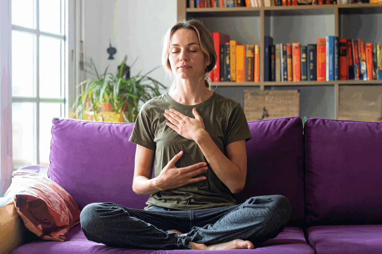 Woman practicing self-compassion with hand on heart in mindful meditation at home