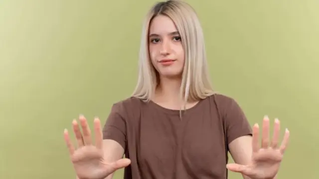 Young woman showing stop gesture with both hands representing setting healthy boundaries as an empath to protect energy and avoid emotional exhaustion