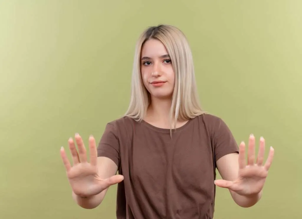 Young woman showing stop gesture with both hands representing setting healthy boundaries as an empath to protect energy and avoid emotional exhaustion