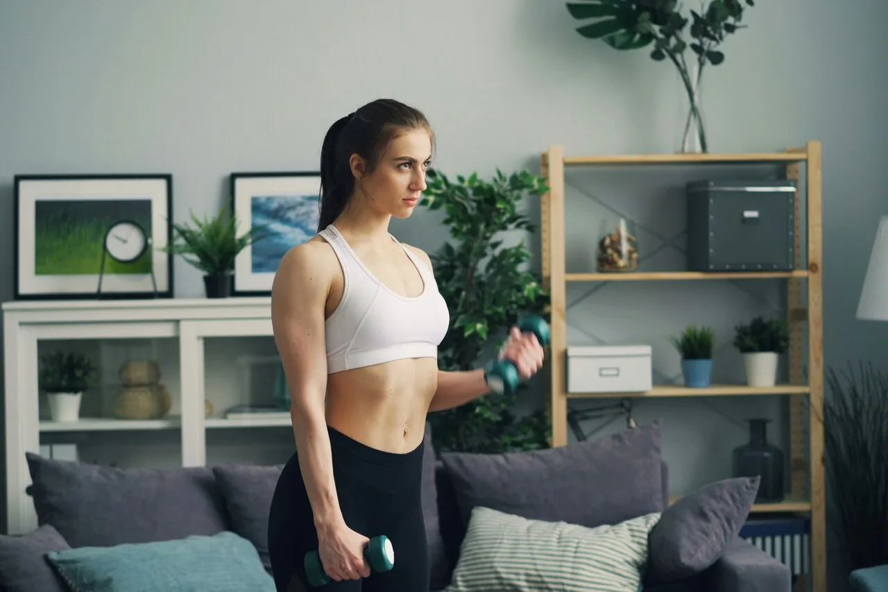 Woman doing strength training with dumbbells at home living room fitness workout