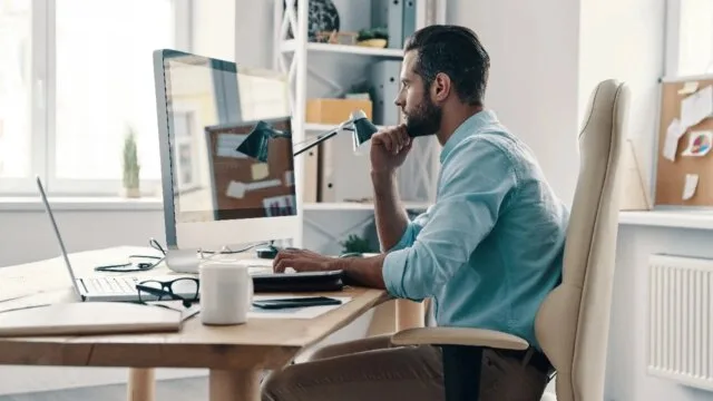 Man focused on single task at computer desk illustrating the benefits of deep work and avoiding multitasking