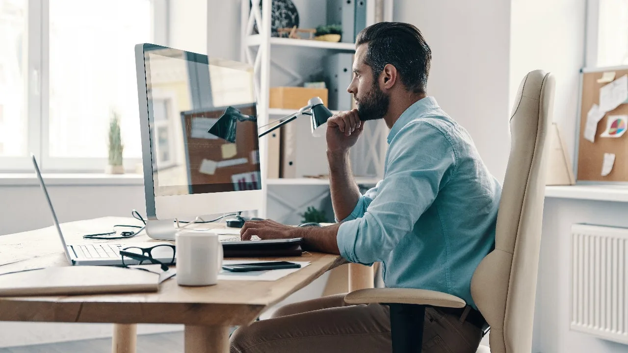 Man focused on single task at computer desk illustrating the benefits of deep work and avoiding multitasking