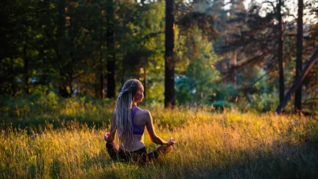 Woman meditating in nature at golden hour representing authentic mindfulness practice beyond wellness culture trends