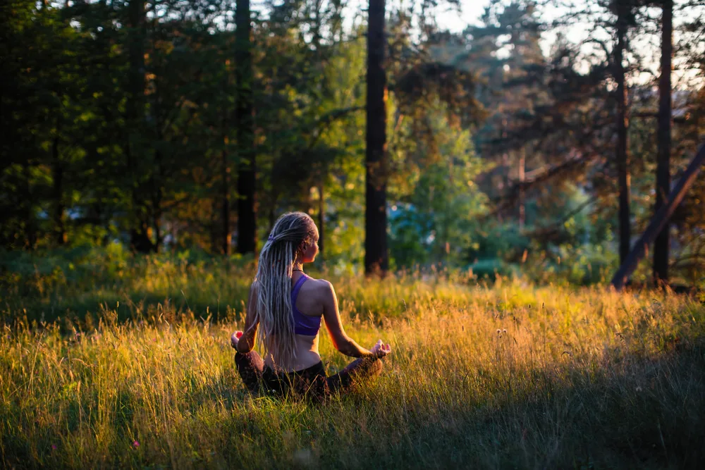 Woman meditating in nature at golden hour representing authentic mindfulness practice beyond wellness culture trends